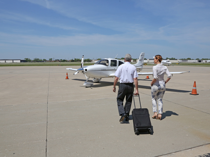 Passenger walking to airplane with pilot.